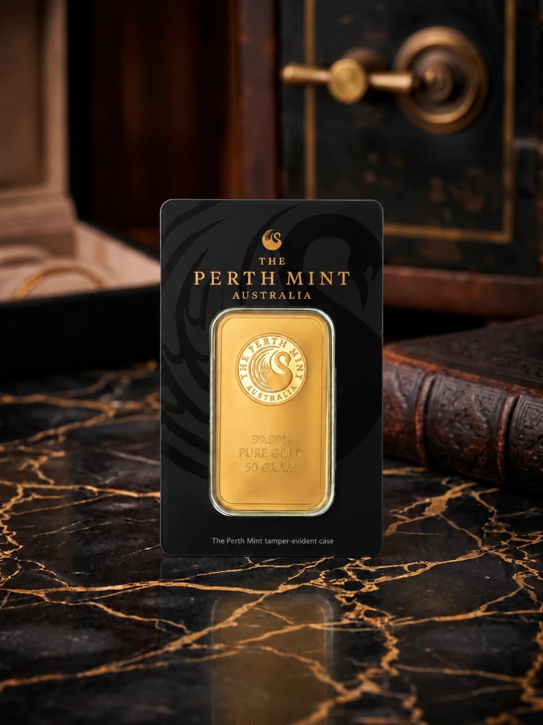 A Perth Mint 50 g gold bar in its tamper-evident case on black and gold marble